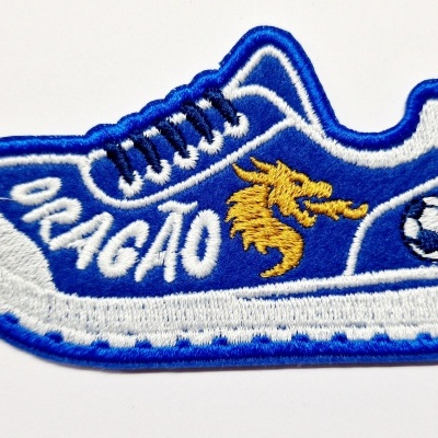 Emblema bordado azul em forma de sapatilha com dragão e bola de futebol