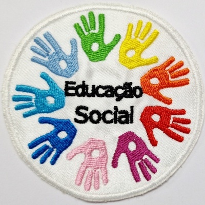 Emblema bordado circular com mãos coloridas e texto Educação Social