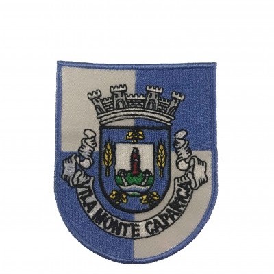 Emblema bordado azul e branco com brasão e texto 'VILA MONTE CARNIÇO'