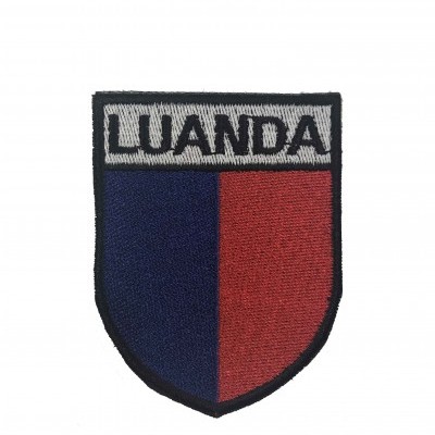 Emblema bordado em formato de escudo com as cores azul, vermelho e cinzento e texto LUANDA
