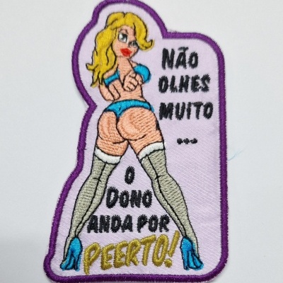Emblema bordado com mulher loira em lingerie azul e texto em português.