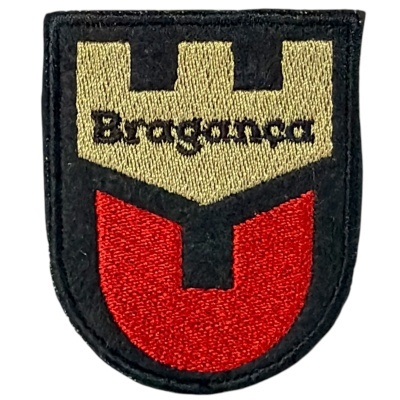 Patch bordado em forma de escudo com cores vermelha, bege e preta com texto