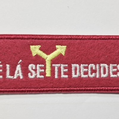 Emblema bordado vermelho com seta amarela e texto branco