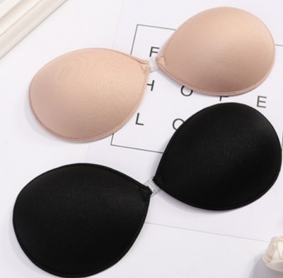 Dois soutiens adesivos, um bege e um preto, sobre uma superfície branca com papel