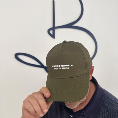 Boné verde-oliva com frase bordada usado por pessoa com camisa azul