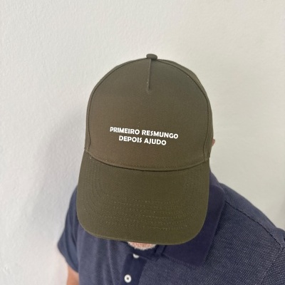 Boné verde-oliva com texto branco e pessoa com camisa azul