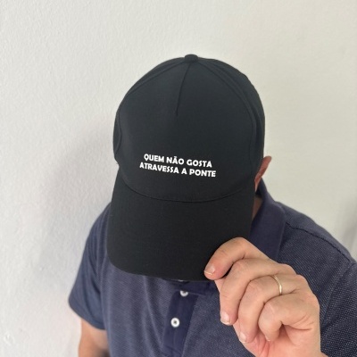 Boné preto com texto branco QUEM NÃO GOSTA ATRAVESSA A PONTE
