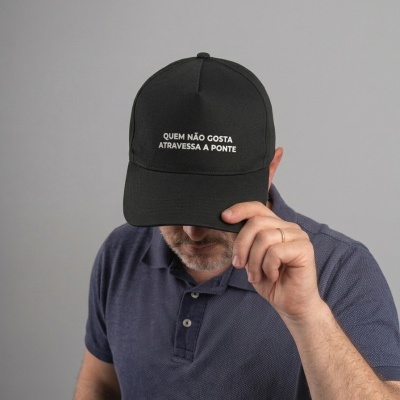 Boné preto com texto branco e homem com camisa azul escuro