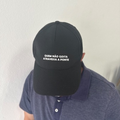 Boné preto com texto branco e pessoa com camisa azul