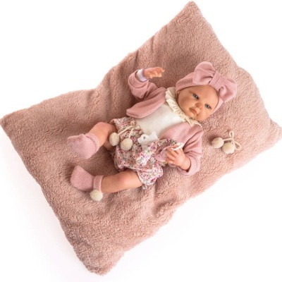 Boneca bebé realista vestida de rosa sobre almofada felpuda rosa
