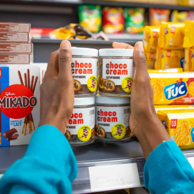 Frascos de choco cream em prateleira de supermercado com embalagens de snacks ao redor