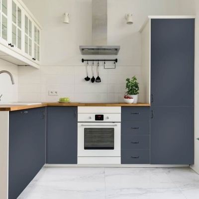 Cozinha moderna com armários cinza-azulados, forno branco, tampo madeira e planta no chão