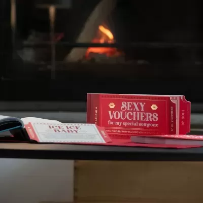 Voucher vermelho SEXY VOUCHERS for my special someone sobre mesa com lareira ao fundo
