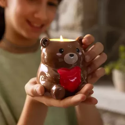 Vela decorativa em forma de urso castanho segurando um coração vermelho