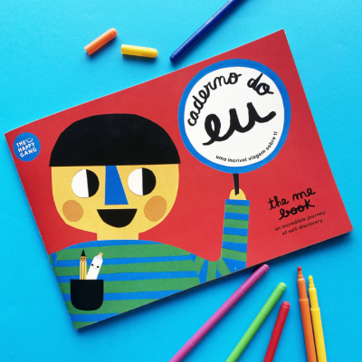 Livro infantil de capa vermelha com personagem ilustrado e marcadores coloridos ao redor sobre fundo azul