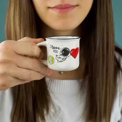 Caneca branca com design de astronauta e texto I love you, segurada por mulher