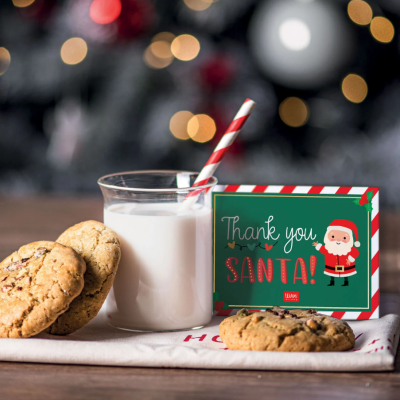 Copo de leite com canudo e bolachas ao lado de caixa decorativa de Natal