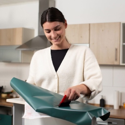 Mulher a embrulhar presente com papel verde numa cozinha moderna