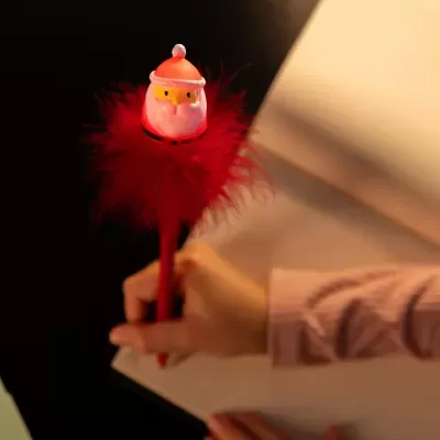 Caneta decorativa de Pai Natal com penas vermelhas na mão