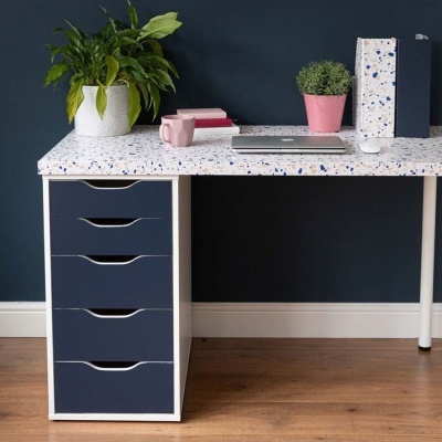 Secretária com tampo terrazzo e gavetas azuis junto a parede azul escura