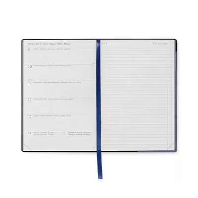 Agenda aberta com capa preta e cordão azul, páginas com texto e pautas