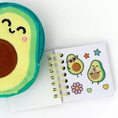 Estojo verde e castanho em forma de abacate com caderno ilustrado com abacates divertidos.