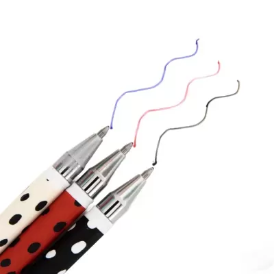 Três esferográficas com pontas metálicas e padrão de pintas em fundo branco.