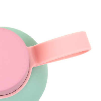 Pote de silicone rosa com tampa e alça sobre base verde-água
