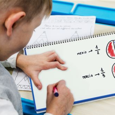 Menino a escrever em caderno com desenhos e frações coloridas.