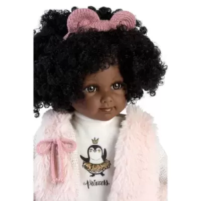Boneca com cabelo afro, laço rosa, colete felpudo rosa e camisola branca com pinguim e texto princess.