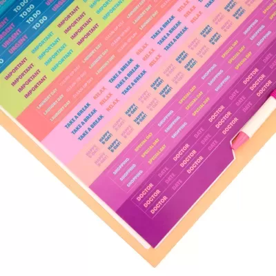 Folha de etiquetas autocolantes coloridas com várias palavras em inglês para organização, ao lado de uma caneta rosa.