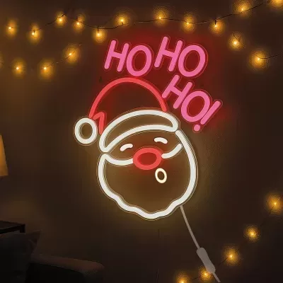 Neon decorativo de Pai Natal iluminado com texto HO HO HO e luzes amarelas num ambiente interior