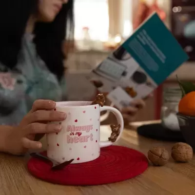 Caneca branca com corações e texto, decoração de ursinhos em relevo, em mesa de madeira com base vermelha