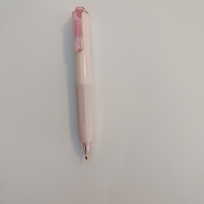 Caneta esferográfica rosa claro com tinta vermelha sobre mesa branca