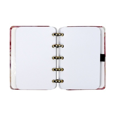 Caderno de argolas aberto com páginas em branco e capa floral rosa