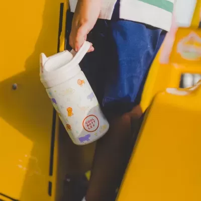 Garrafa infantil estampada com animais e texto COOL BOTTLES na mão de criança