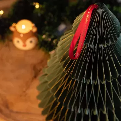 Árvore de Natal em papel verde com fita vermelha e luz ao fundo