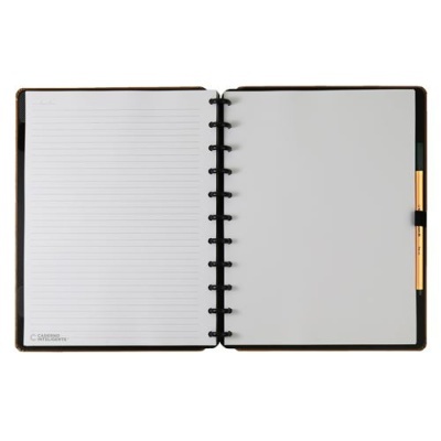 Caderno preto aberto com página pautada e página em branco, caneta dourada ao lado