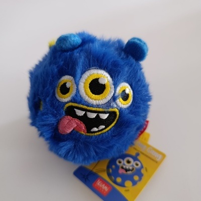 Pelúcia azul com três olhos e boca sorridente