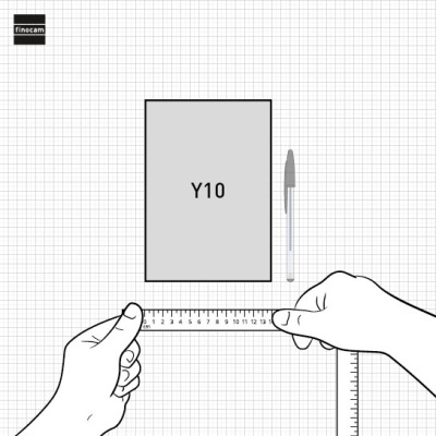 Mãos segurando régua plástica transparente junto a bloco cinzento com texto Y10 e caneta numa superfície com papel quadriculado