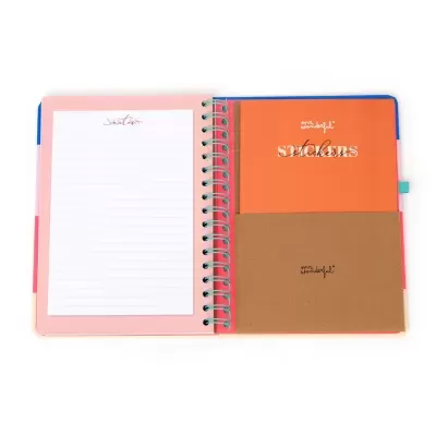 Caderno espiral aberto com bloco de notas e envelope de cartolina no interior.