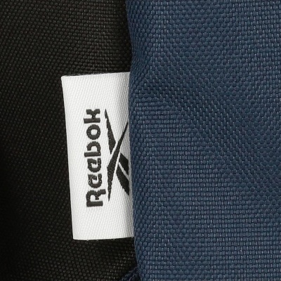 Etiqueta branca Reebok entre tecido preto e azul escuro