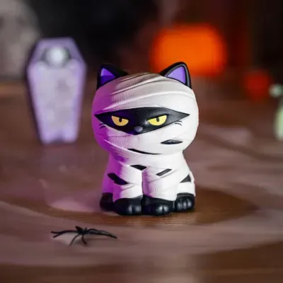 Boneco decorativo de gato preto tipo múmia com faixas brancas e olhos amarelos