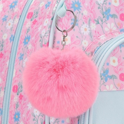 Chaveiro pompom cor-de-rosa pendurado num mochila floral azul e rosa
