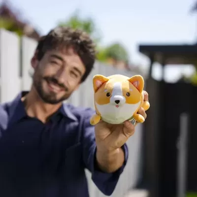 Figura decorativa de cão em cerâmica laranja e branca segurada por pessoa