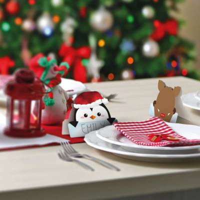 Mesa decorada para Natal com marcadores de lugar, guardanapo riscado, prato e lanterna vermelha