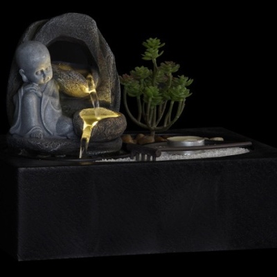 Fonte de água decorativa com figura de monge e planta em fundo preto