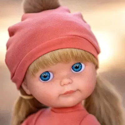 Boneca com cabelo louro, olhos azuis, roupa e gorro cor-de-rosa com pompom