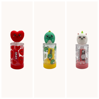 Três lip balms com tampas de silicone decorativas e embalagens transparentes com desenhos cartoon.
