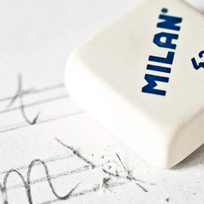 Borracha branca com texto azul MILAN 430 sobre papel branco com marcas de lápis